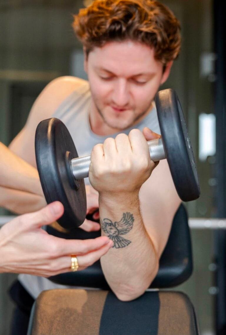 Close-up of a client performing a dumbbell bicep curl with coaching support