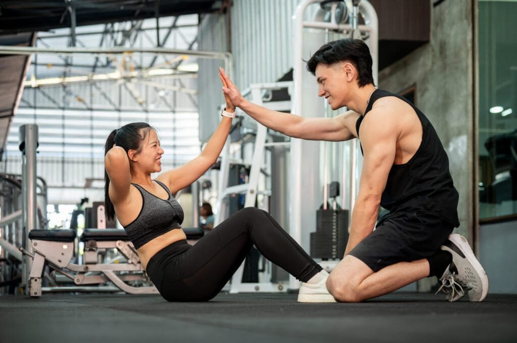 English-speaking personal trainer giving a client a high five during a workout in Bangkok