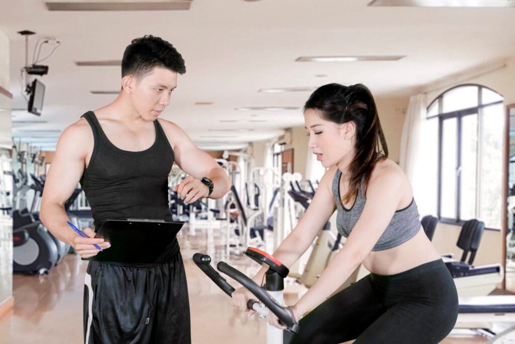Personal trainer cost in Bangkok: coach timing a client's exercise set