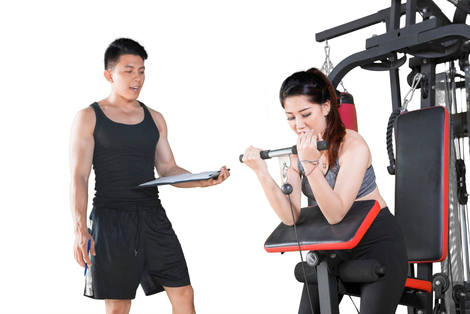 Woman exercising on gym equipment with her coach